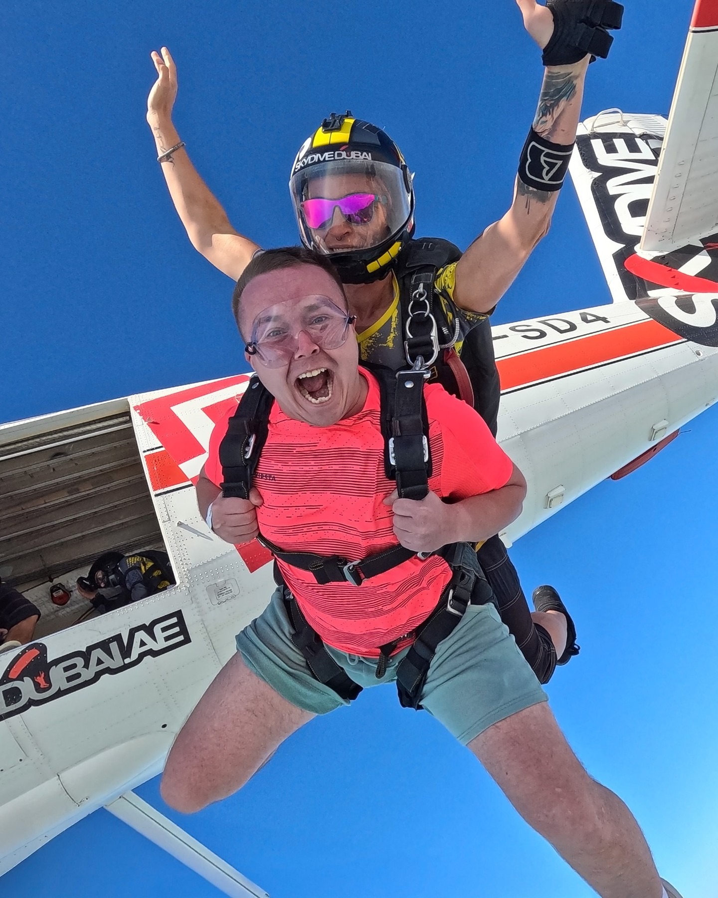 Excited tandem skydiver jumping from airplane in Dubai