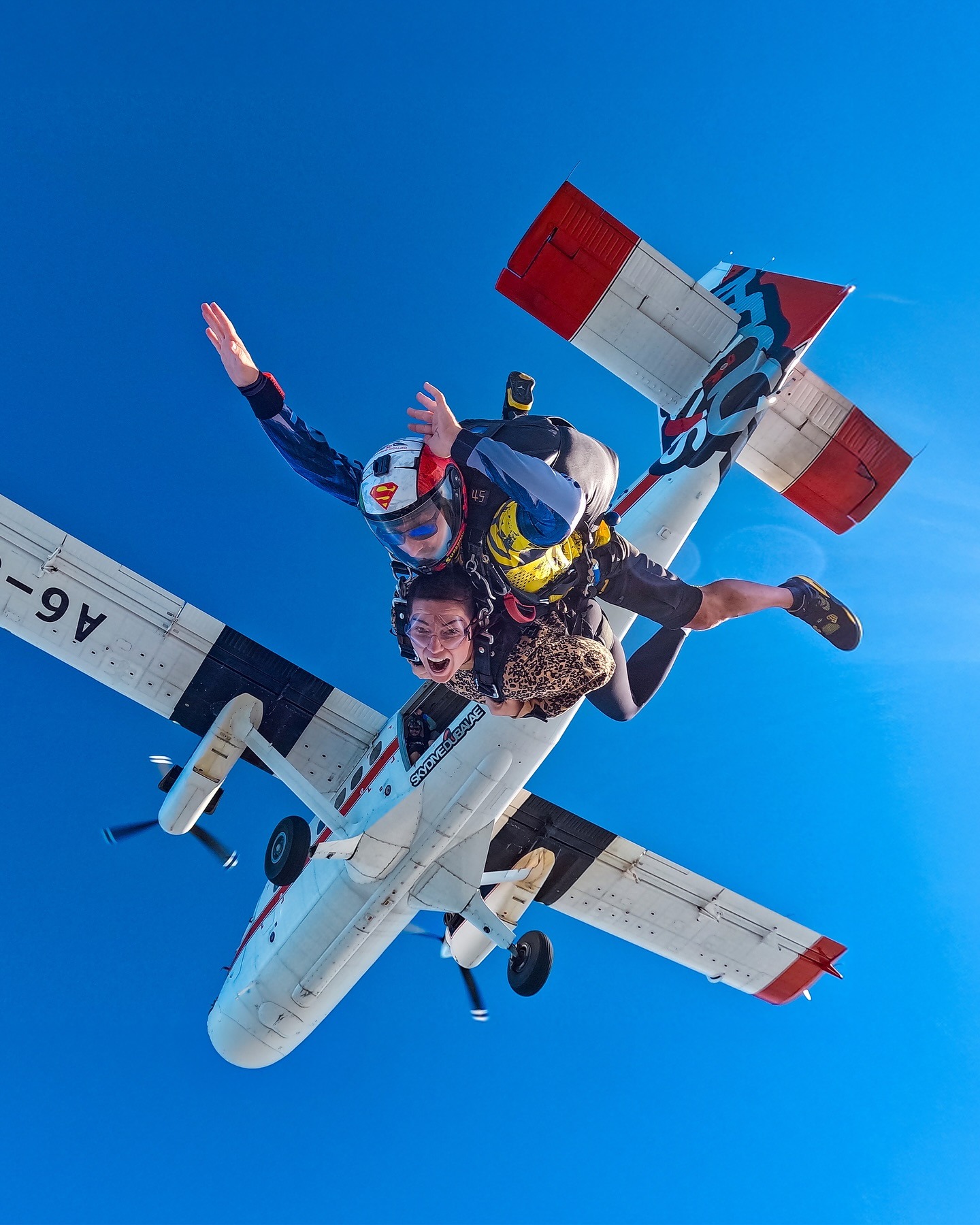 tandem skydivers exiting aircraft over Dubai blue sky