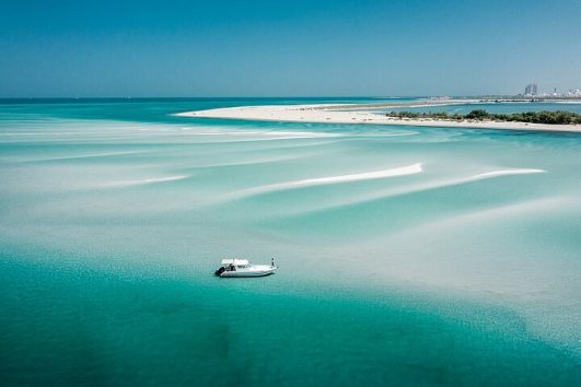 Aerial view of a private boat anchored near white sandbanks surrounded by turquoise shallow waters in the Arabian Gulf near Abu Dhabi