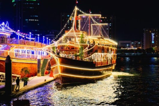 Traditional wooden dhow cruise illuminated at night on Dubai Creek