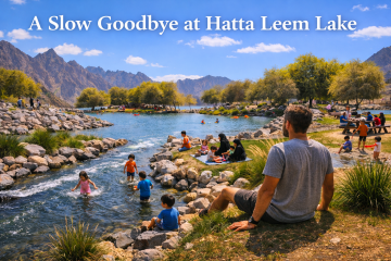 Families picnicking and children playing by the flowing water at Hatta Leem Lake with mountains in the background