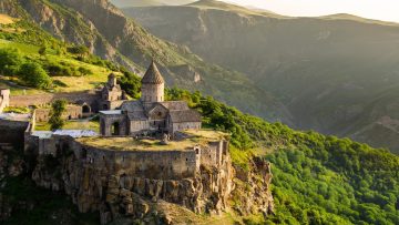 Tatev Monastery perched on a cliff surrounded by green mountains in Armenia