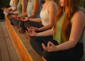 Group practicing meditation outdoors on wooden deck
