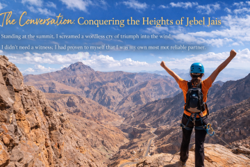 Female climber standing triumphantly on a mountain peak at Jebel Jais in Ras Al Khaimah
