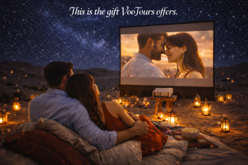 Romantic couple watching a private movie in the Dubai desert under a starry sky with lanterns and projector setup