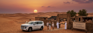 VooTours 4x4 vehicle arriving at Ezba desert camp at sunset with guests and Bedouin hosts