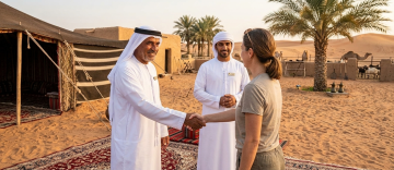 Emirati host shaking hands with visitor at traditional desert Ezba camp