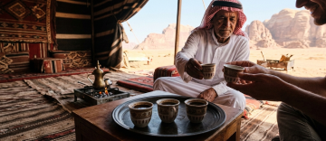 Traditional Arabic coffee cups being exchanged inside Bedouin tent at desert camp