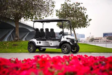 large multi passenger golf cart parked near waterfront with city background