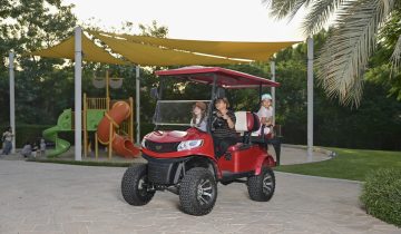 family riding golf cart near playground in residential park