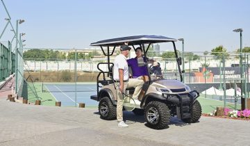 golf cart parked near tennis court with players talking