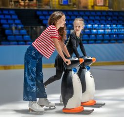 kids skating together using penguin aids at Dubai Ice Rink