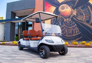 modern electric golf cart parked near contemporary building with artistic wall