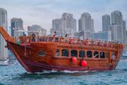 Traditional dhow sailing through Dubai Marina with skyscrapers in the background.