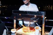 Chef preparing BBQ brisket at a live station onboard the Royal Dhow Cruise.