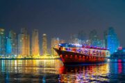 Brightly illuminated dhow cruise with Dubai Marina skyline