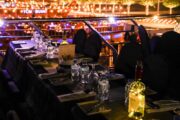 Night dining setup on the dhow cruise with vibrant city lights in the background.