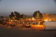 desert chalets and illuminated trees reflecting in a serene pond