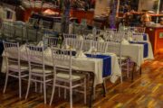 Elegant dining tables with white chairs and blue accents arranged for guests on a dhow