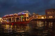 Illuminated Dhow Cruise floating on Dubai Creek at night.