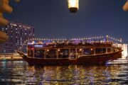 Dhow cruise lit with decorative lights, reflecting in the waters of Dubai Creek.