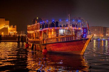 Dhow cruise boat docked near Dubai Creek buildings.