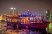 Close-up of a decorated dhow cruise anchored at Dubai Creek, illuminated at night.