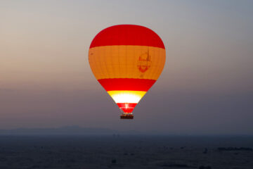 Hot air balloon soaring over Dubai's desert at sunrise