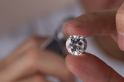 Close-up of a person holding a polished diamond between fingers.