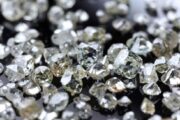 Close-up view of various uncut and rough diamonds on a black surface