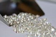 Pile of loose diamonds being sorted with a metal tray.