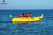 A group of friends in red life jackets on a Banana Ride in calm waters.