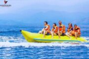 A group of people enjoying a Banana Ride with orange life jackets on blue waters.