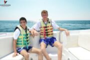 Two friends relaxing on a luxury boat with life vests on.