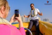 Woman capturing a happy moment of a man posing on a boat.