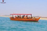 Wooden boat cruising near a serene shoreline.