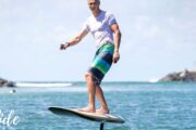 A rider standing confidently on an e-Foil board, gliding smoothly above the ocean.