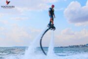 A fly boarder hovering above the water with jets of water propelling them skyward.