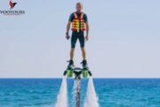 A fly boarder standing confidently above the water on a Fly Board, wearing a life jacket.