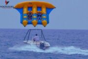 A Fly Fish inflatable ride being towed by a speedboat over open waters.