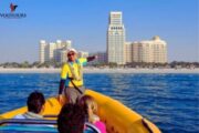 Tour guide pointing out landmarks to passengers on a yellow speedboat.