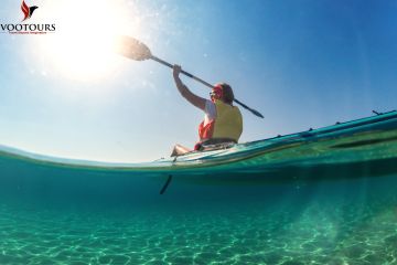 A view of a kayaker paddling on turquoise waters from beneath the surface.