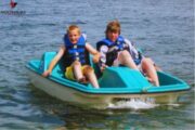 wo kids paddling a pedal boat on calm waters.