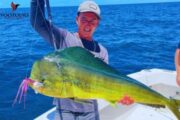 Fisherman holding a vibrant Mahi-Mahi on a deep-sea fishing boat