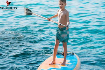 A young boy enjoying paddleboarding on the sparkling waters of Ras Al Khaimah.