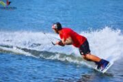 Athlete gliding on a wakeboard over calm water.