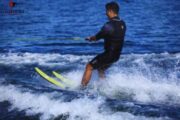 A man water skiing on neon-yellow skis, creating a spray of water as he glides.