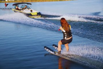 A back view of a water skier following a speedboat, leaving a trail of waves.