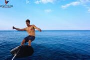 A man in action while riding an e-Foil board, leaning into a turn above the water.