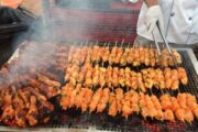 Grilled chicken and kebabs on a barbecue grill in a desert camp.